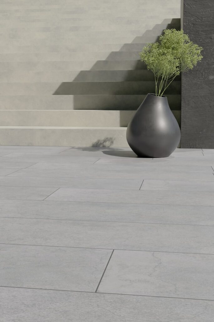 a vase with a plant in it sitting on the ground